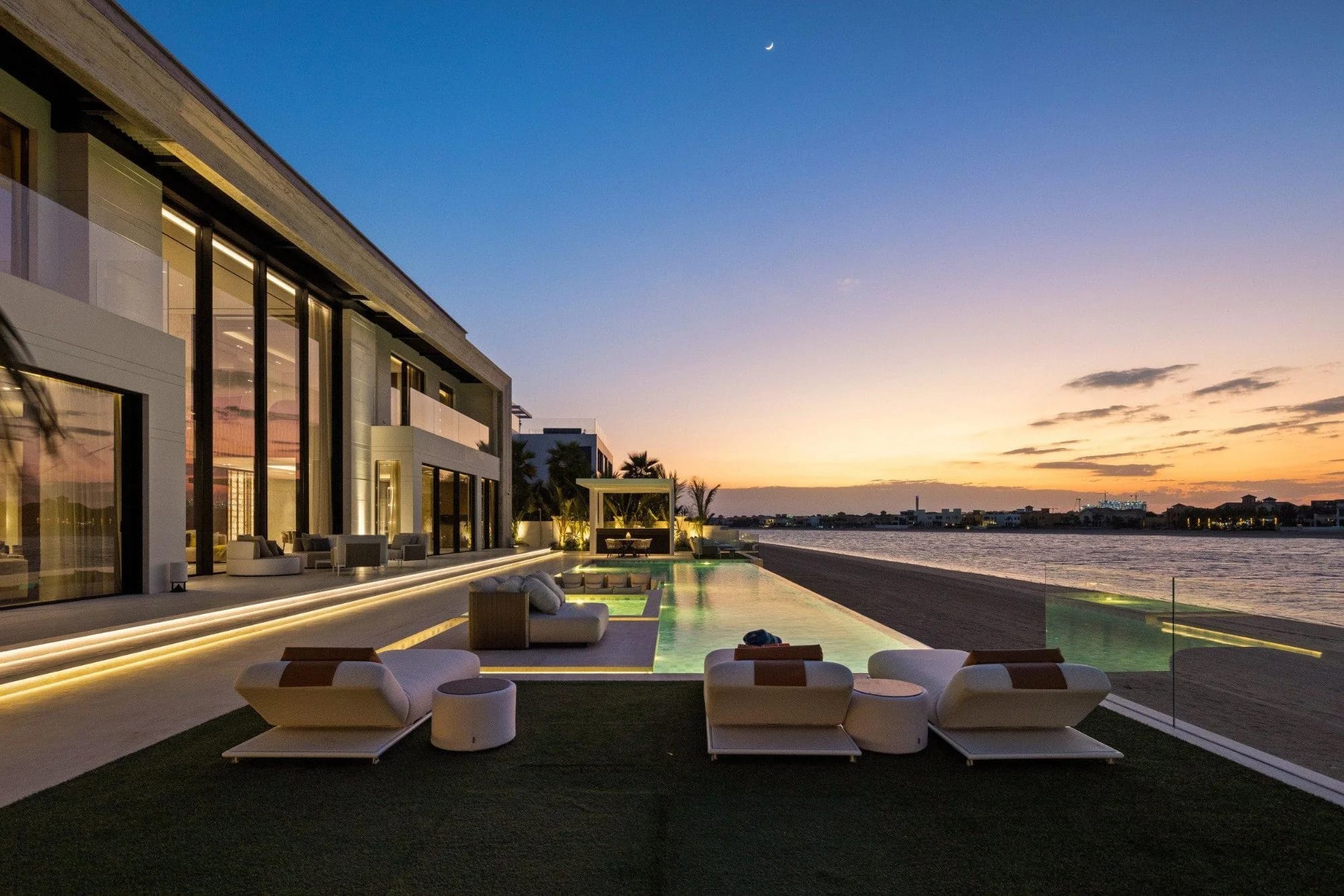 Luxury waterfront villa with a pool at sunset